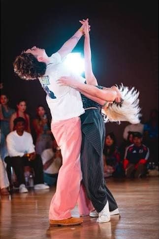 A couple mid-dip in a Jack & Jill final, the crowd watching from the floor
